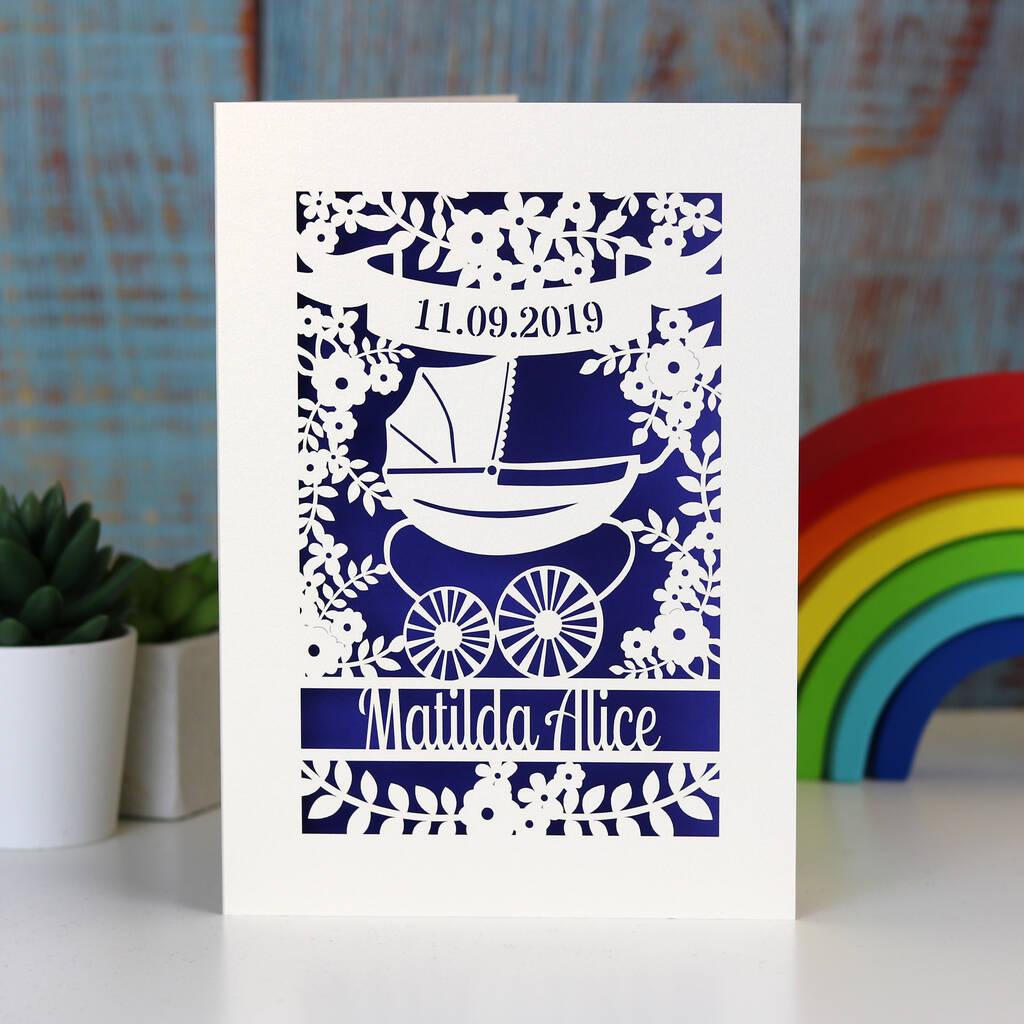 A laser cut baby card, gender neutral and personalised. Design shows a vintage pram surrounded by a floral border.