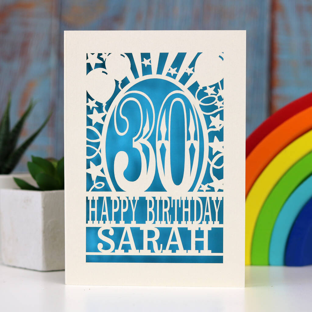 A cream and blue laser cut birthday card. Card shows 30, surrounded by stars and balloons, and reads Happy Birthday and a name.