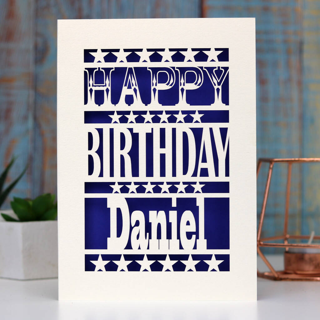 A paper cut birthday card for him. Happy Birthday Daniel is written on the front of the card. Card can be personalised with any name. Stars separate each line of text and background is violet.