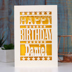 A birthday card personalised with a name and laser cut from cream with yellow behind. 