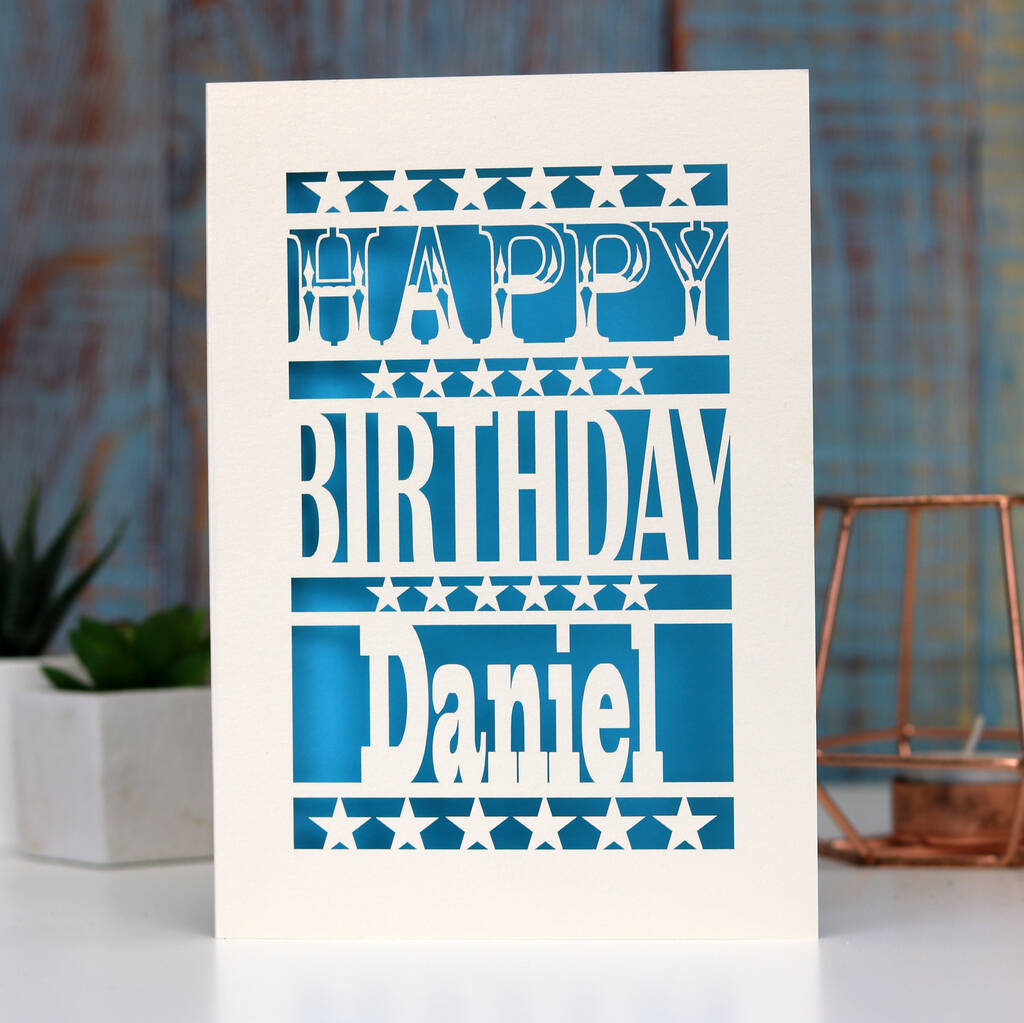 Personalised paper cut birthday cards. This cream and blue card says Happy Birthday, with a name at the bottom. 