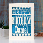 Personalised paper cut birthday cards. This cream and blue card says Happy Birthday, with a name at the bottom. 