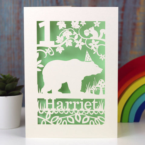 Personalised papercut bear birthday card. Shows a bear wearing his party hat beneath branches, leaves and a squirrel.  Laser cut from cream card with a green insert paper and personalised with a name and age.. - A5 (large) / Light Green