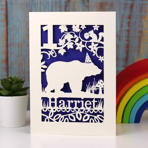Papercut birthday card showing a bear wearing a hat. Also a squirrel in a tree with branches and leaves. Can be personalised with a name and age.  Laser cut from cream card and finished with dark blue insert paper.  - A5 (large) / Infra Violet