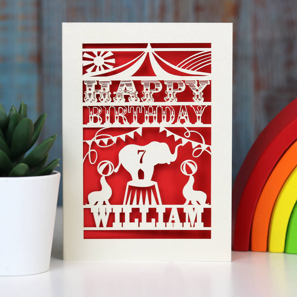 Elephant and seals at the circus on this fun personalised papercut birthday card. Shown cut from cream card with a bright red insert paper. Personalised with age and name.