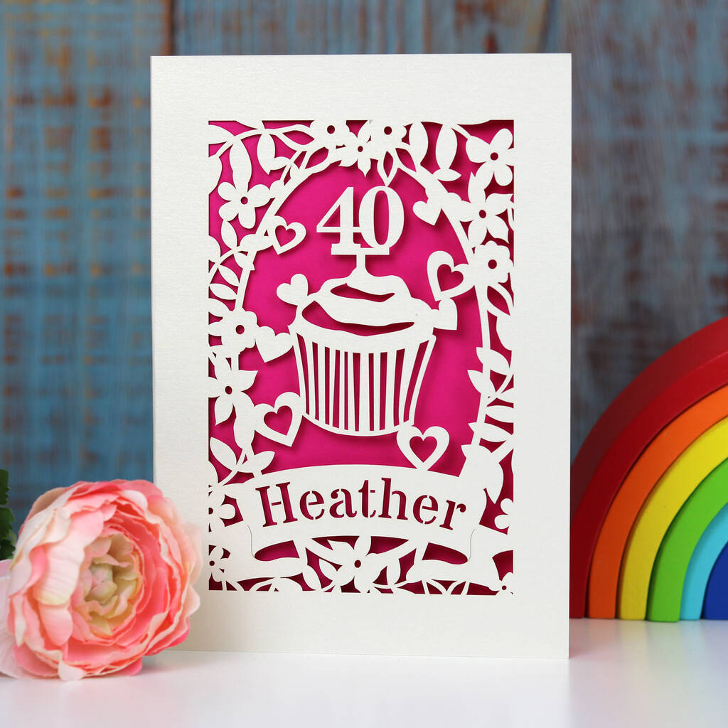 Personalised 40th birthday paper cut card showing a cupcake with an age topper , hearts, leaves and flowers.  Lasercut from cream card and finished with a shocking pink insert.