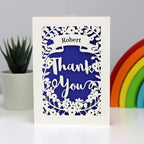 Laser cut Thank You card in cream and infra violet.  Personalised in a banner with Thank you in large letters surrounded with flowers.